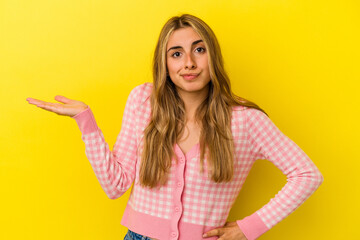 Fototapeta na wymiar Young blonde caucasian woman isolated on yellow background doubting and shrugging shoulders in questioning gesture.