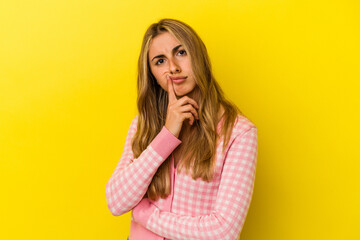 Young blonde caucasian woman isolated on yellow background unhappy looking in camera with sarcastic expression.
