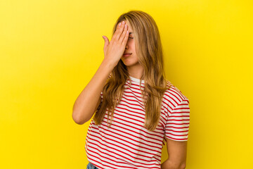 Young blonde caucasian woman isolated on yellow background having a head ache, touching front of the face.