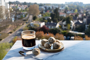 Close-up of a cup of coffee with cream on a terrace overlooking the city
