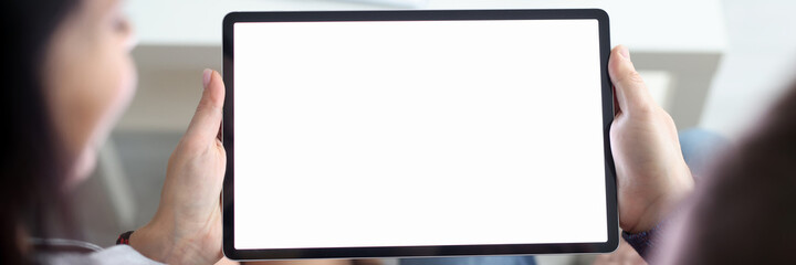 Fototapeta premium Woman and man are sitting on couch at home and holding tablet in their hands closeup