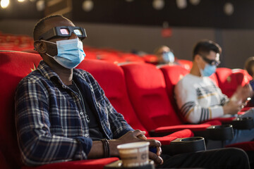 People sit in the cinema hall and watch a movie wearing medical masks and keep their distance. Covid-19 and the film industry