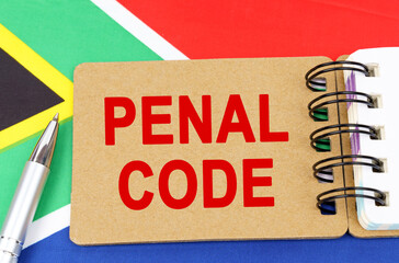 Against the background of the flag of South Africa lies a notebook with the inscription -PENAL CODE