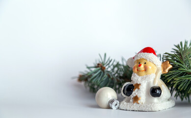 Closeup of Christmas composition of snowman, red ball and fir branch on white background. Merry Christmas card. Winter holiday xmas theme. Happy New Year. Space for text.