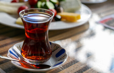 Turkish red aromatic tea in traditional authentic glass cup - armudu on table close-up with blurred dish in background. Brewing tea is an indispensable pleasure for Turks,  photo with copy space area