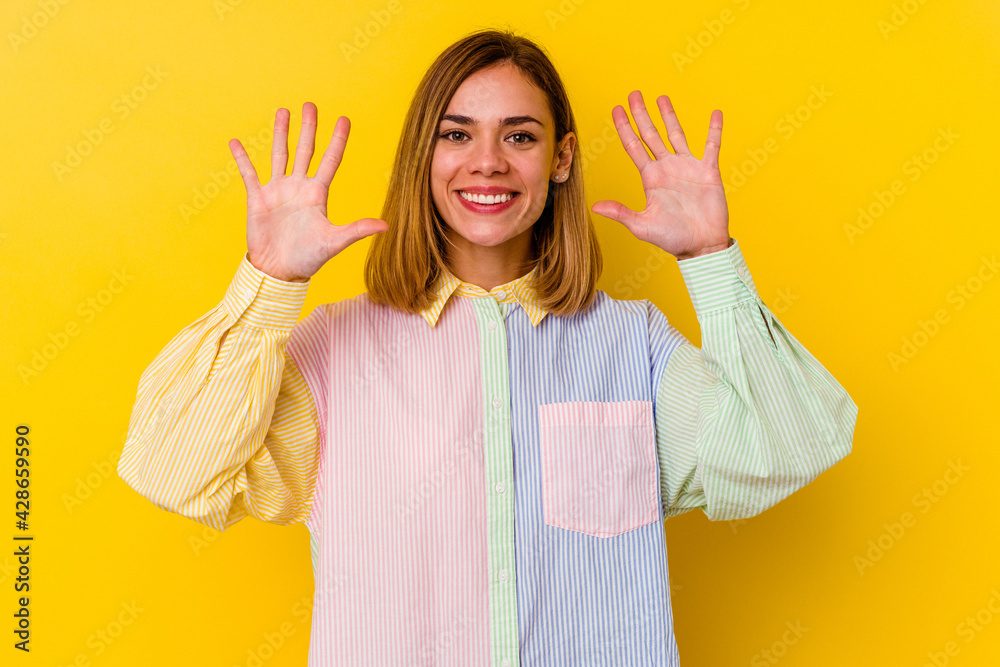 Wall mural young caucasian skinny woman isolated on yellow background showing number ten with hands.