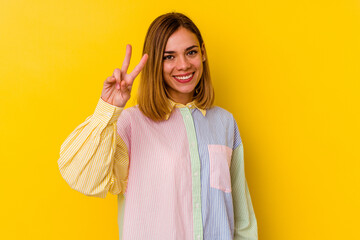 Young caucasian skinny woman isolated on yellow background joyful and carefree showing a peace symbol with fingers.