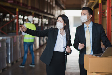 Portrait Young Asian man and woman owner manager stand talking near shelf product box in big warehouse factory store which smile and felling happy, logistic import and export transportation concept