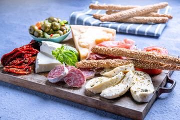 typical Italian antipasto with salami and cheese with bread stick on a cutting board