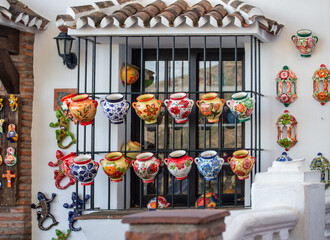 Many colorful ceramic jugs painted with flowers on a background of a brick wall
