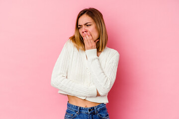 Young caucasian woman isolated on pink background yawning showing a tired gesture covering mouth with hand.