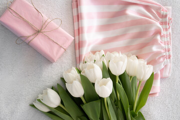 satin white and pink pyjamas, gift wrapped in pink paper and a bouquet of white tulips