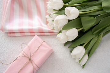satin white and pink pyjamas, gift wrapped in pink paper and a bouquet of white tulips
