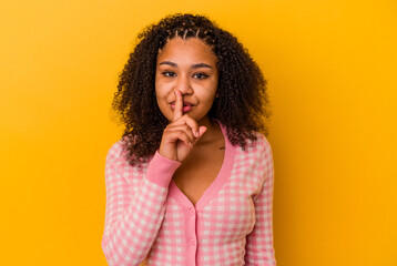 Fototapeta na wymiar Young african american woman isolated on yellow background keeping a secret or asking for silence.