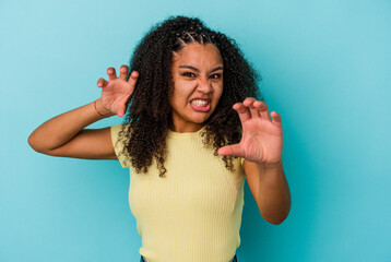 Young african american woman isolated on blue background upset screaming with tense hands.