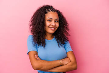 Young african american woman isolated on pink background who feels confident, crossing arms with determination.