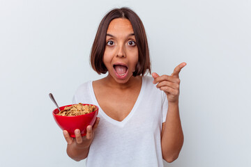 Young mixed race woman eating cereals isolated on white background having an idea, inspiration concept.