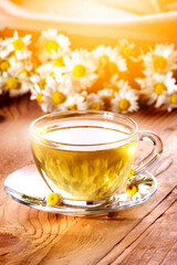 Cup of hot herbal tea with chamomile flowers on a wooden table
