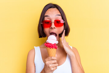Young mixed race woman holding an ice cream isolated on yellow background