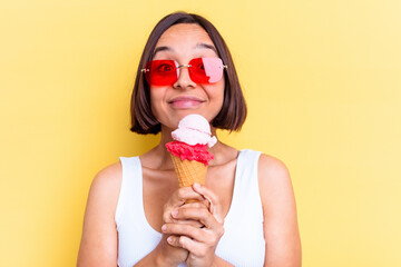 Young mixed race woman holding an ice cream isolated on yellow background