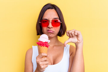 Young mixed race woman holding an ice cream isolated on yellow background