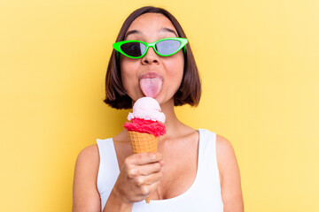 Young mixed race woman holding an ice cream isolated on yellow background