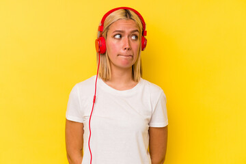 Young venezuelan woman listening music isolated on yellow background confused, feels doubtful and unsure.