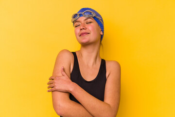 Young swimmer venezuelan woman isolated on yellow background hugs, smiling carefree and happy.