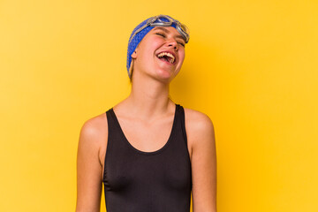 Young swimmer venezuelan woman isolated on yellow background relaxed and happy laughing, neck stretched showing teeth.