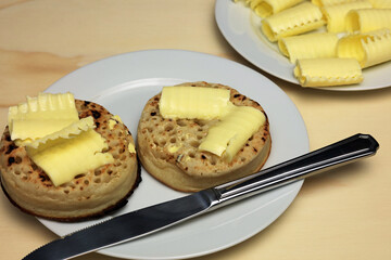 Crumpets With Melting Butter swirls Served On A White Tea Plate.