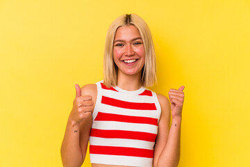 Young venezuelan woman isolated on yellow background raising both thumbs up, smiling and confident.