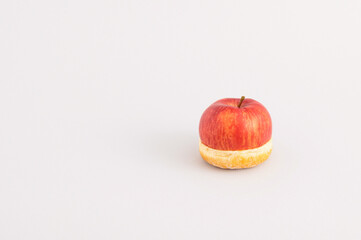 Creative food concept with half apple and half donut isolated on grey background