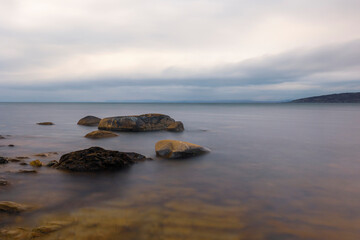 Fototapeta na wymiar Long exposure horizontal photograph, sea horizon, Three large stones protruding from the water.
