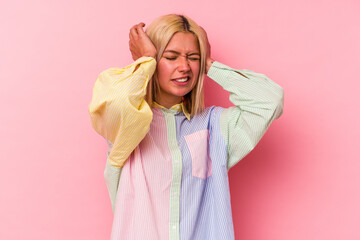 Young venezuelan woman isolated on pink background covering ears with hands.