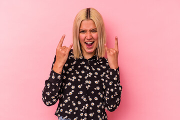 Young venezuelan woman isolated on pink background showing a horns gesture as a revolution concept.