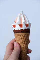 female hand holds a waffle cone with delicious popsicles poured with sweet syrup, concept of happy childhood, impressions, limiting sweets and sugar in childrens food