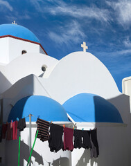 Clothes are drying near beautiful blue-domed Greek Orthodox church in Chora, the capital of Ios island, Cyclades, Greece