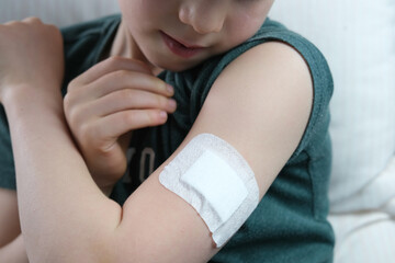 little patient in shirt, white plaster on the hand, child, boy made medical vaccine, concept of vaccination of the population against virus COVID-19