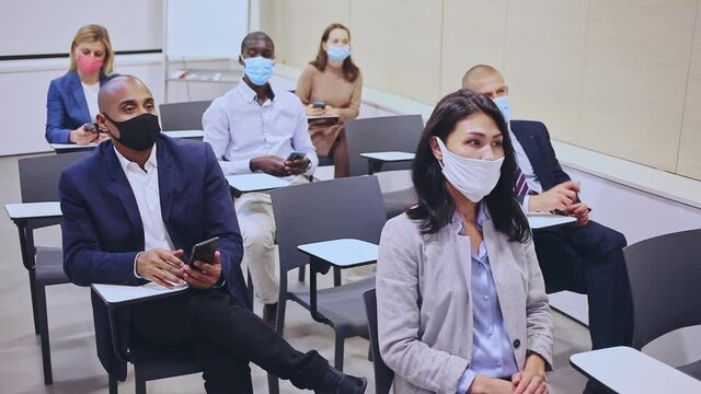 Side view of a group of businessmen in protective masks undergoing training under the guidance of a teacher