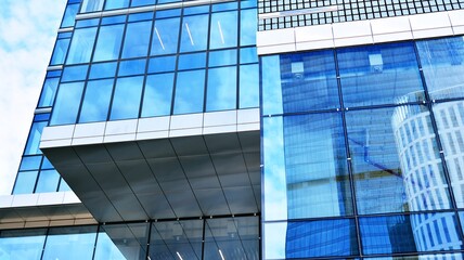 Abstract closeup of the glass-clad facade of a modern building covered in reflective plate glass. Architecture abstract background. Glass wall and facade detail. Velvia graphic filter.