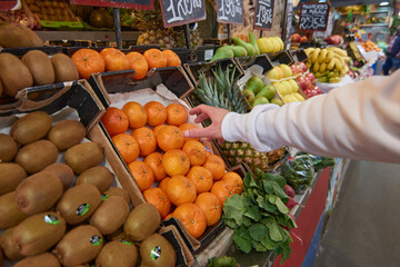 A hand grabbing an orange at a fruits and vegetable market