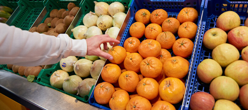 A hand grabbing an orange at a fruits and vegetable market