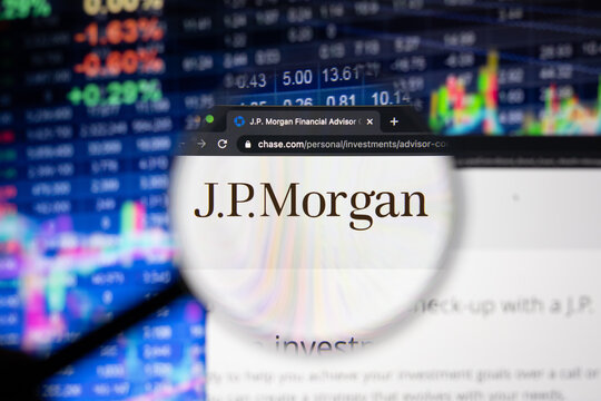 J.P.Morgan company logo on a website with blurry stock market developments in the background, seen on a computer screen through a magnifying glass
