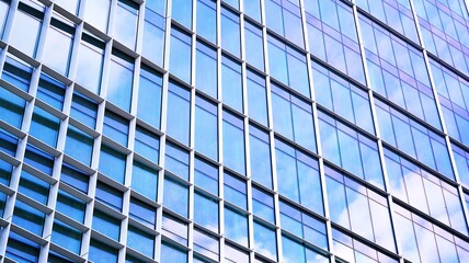 Abstract closeup of the glass-clad facade of a modern building covered in reflective plate glass. Architecture abstract background. Glass wall and facade detail. Velvia graphic filter.