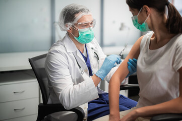 Fototapeta premium In a medical laboratory, a young woman is vaccinated against coronavirus during a pandemic