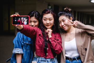 Portrait of a group of asian women friends taking a selfie with a mobile phone together.