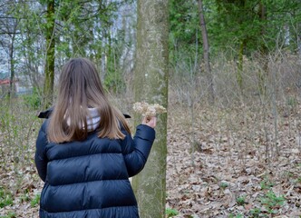 Girl on a walk in the forest, admiring dry flowers.	