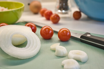 Close-up of onion rings. Preparing a salad with onions and cherry tomatoes.