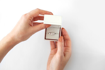 Female hands open a white box with a diamond ring on a white background. Proposal to get married. Diamond engagement ring in a white box
