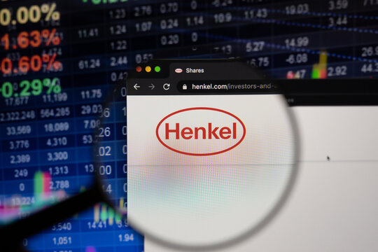 Henkel company logo on a website with blurry stock market developments in the background, seen on a computer screen through a magnifying glass